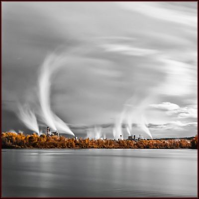 Wispy smoke rising from stacks across a river